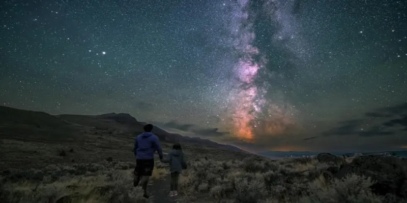 Starry night sky over a dark
landscape