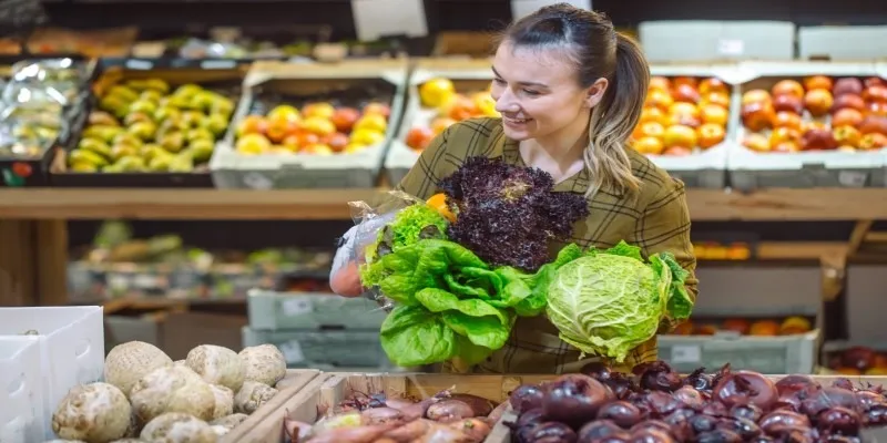 A shopper holding a basket filled with fresh produce walking through Whole Foods